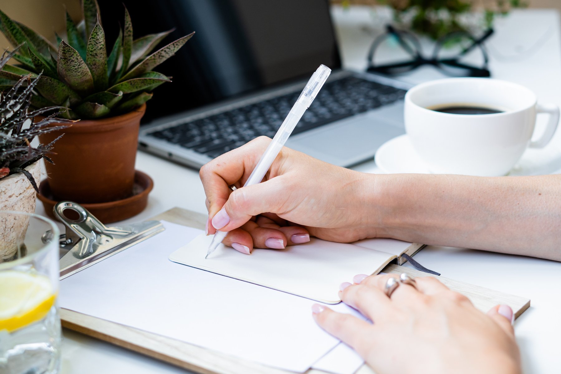 Woman's Hands Writing Notes in a Notepad with a Pen